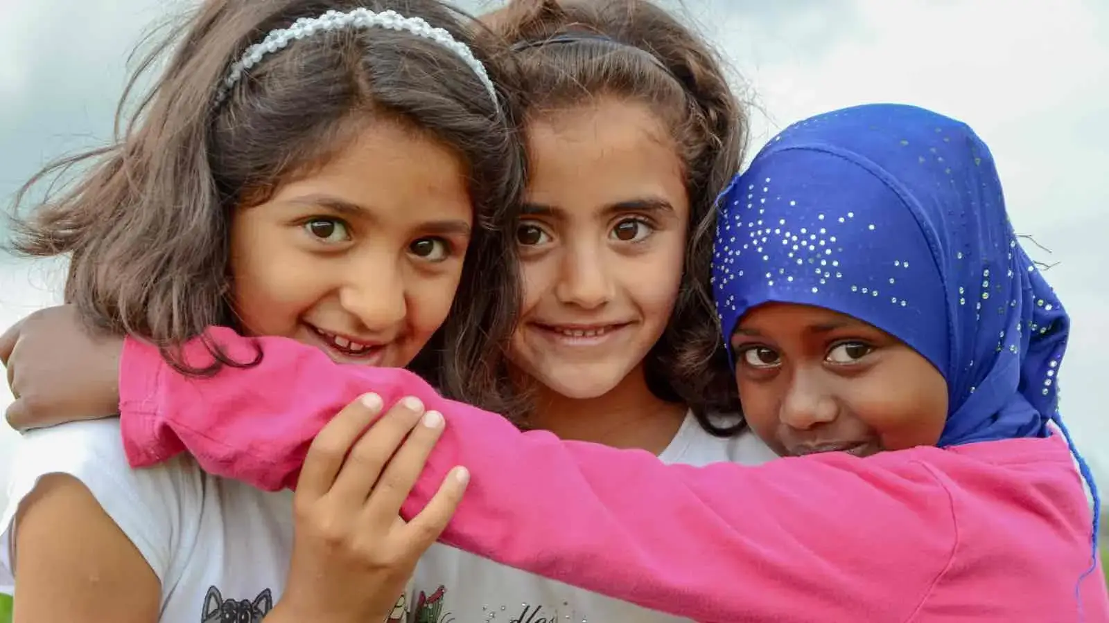 Drei Mädchen mit Migrationshintergrund lächeln in die Kamera
