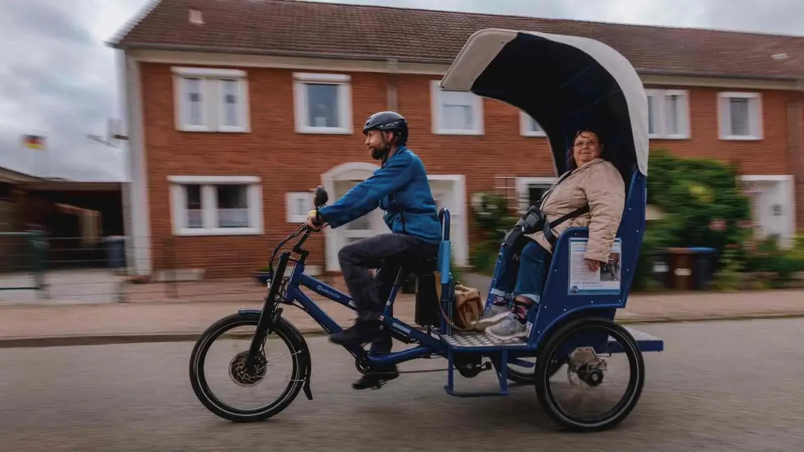 Eine Fahrrad-Rikscha mit einem Fahrer und einer Frau als Fahrgast fahren auf der Straße
