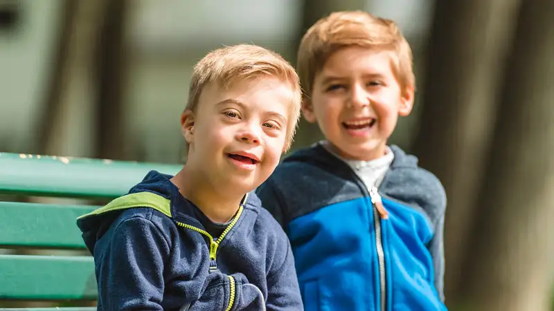 Zwei Jungen mit und ohne Behinderung blicken selbstbewusst in die Kamera