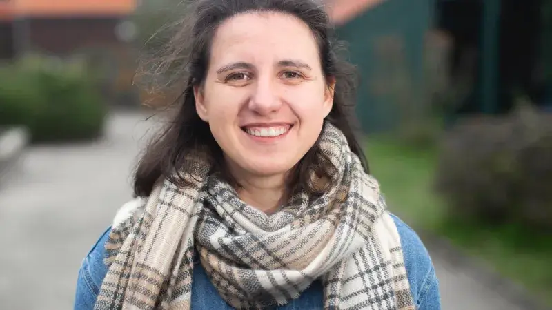 Eine junge Frau mit Schal lächelt in die Kamera