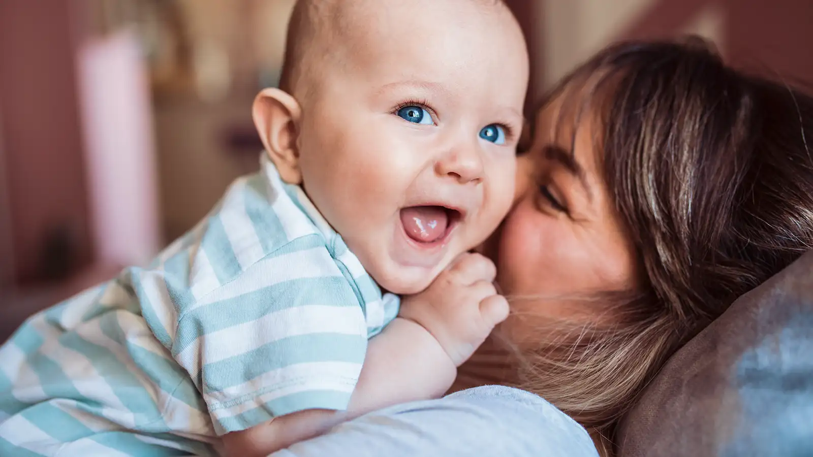 Ein lachendes Baby liegt auf dem Oberkörper seiner Mutter.