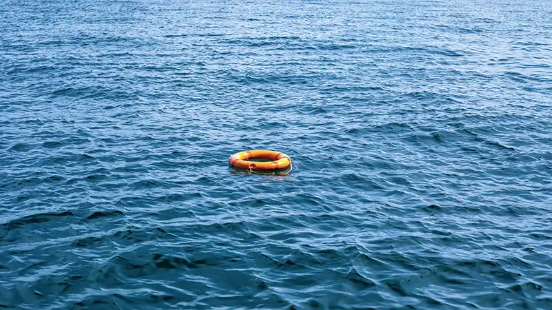 Ein einzelner oranger Rettungsring schwimmt auf der unruhigen Wasseroberfläche des Meeres.