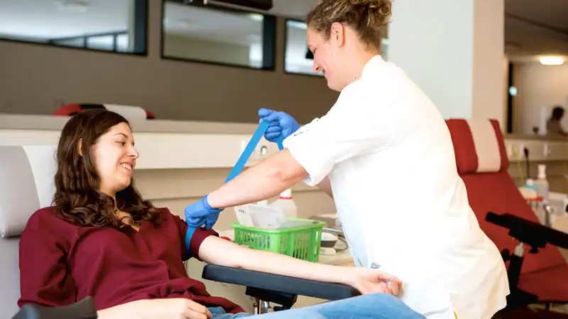 Eine Frau spendet Blut, während medizinisches Personal sie betreut.