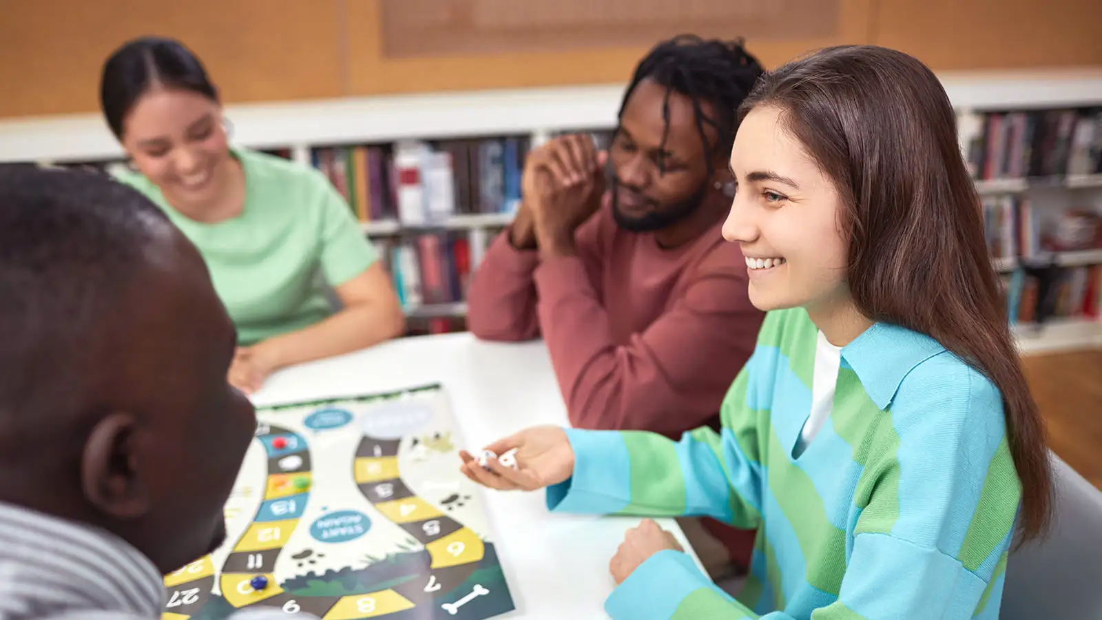 Vier Personen sitzen um einen Tisch und spielen gemeinsam ein Brettspiel.